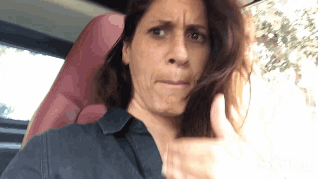 a woman in a car making a funny face with her hand