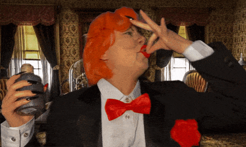 a woman in a tuxedo and red bow tie is drinking from a glass