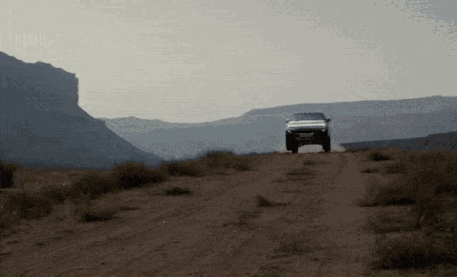 a white truck is driving down a dirt road