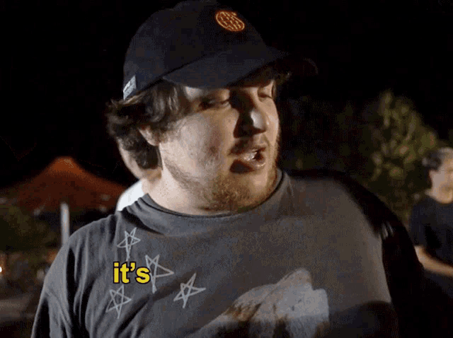a man wearing a black hat and a shirt that says it 's