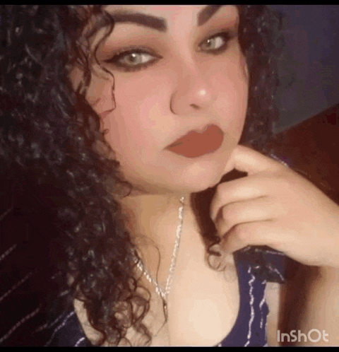 a woman with curly hair is wearing a necklace