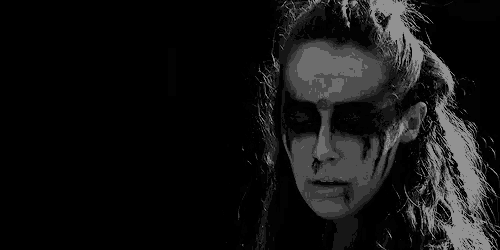 a black and white photo of a woman with face paint .