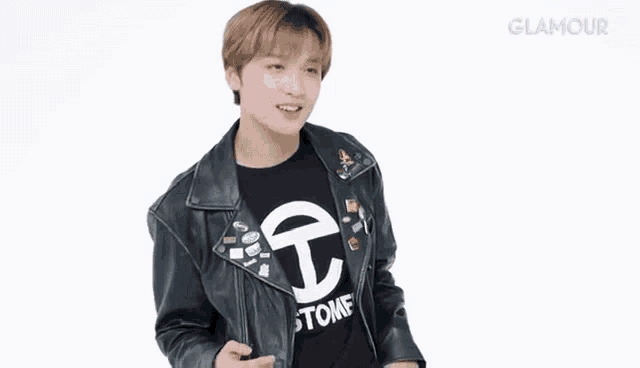 a young man wearing a black leather jacket and a black t-shirt is standing in front of a white background .