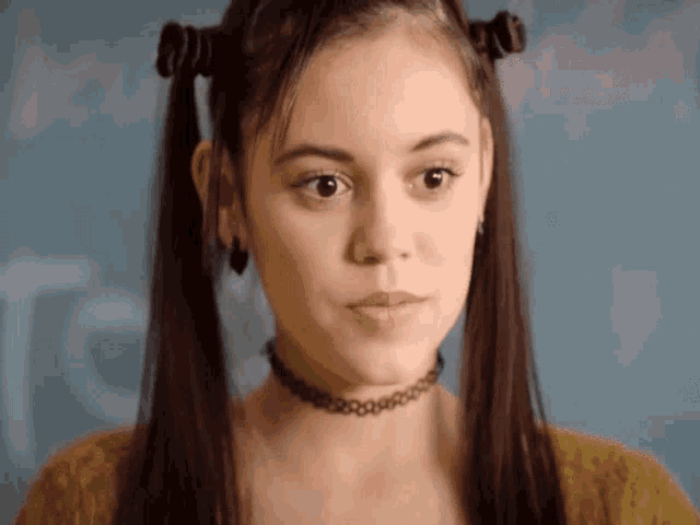 a girl with pigtails and a choker looks serious