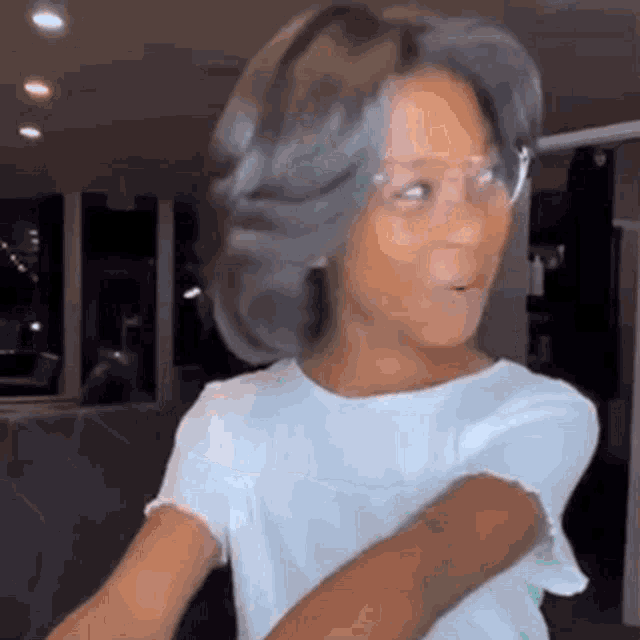 a young girl wearing glasses and a wig is standing in a room .
