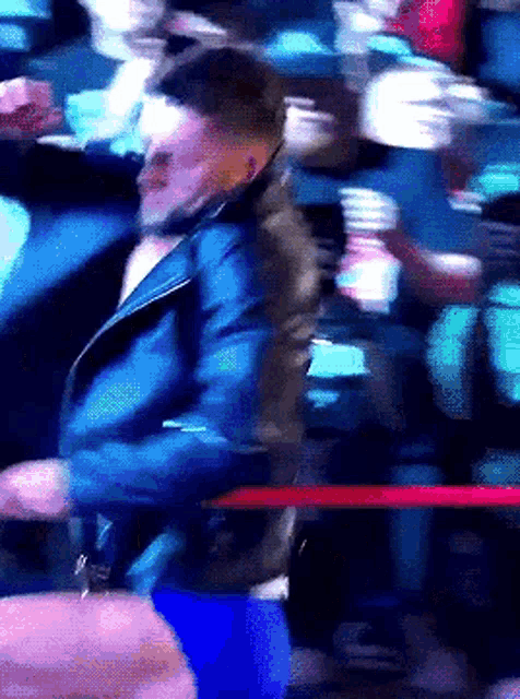 a man in a blue jacket is dancing in front of a crowd of people