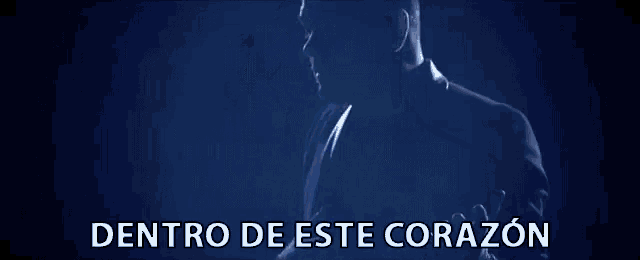 a man stands in a dark room with the words dentro de este corazon below him
