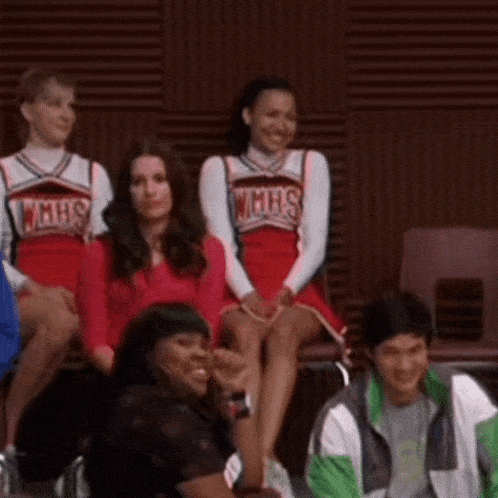 a group of cheerleaders wearing wmhs uniforms are sitting in a stadium