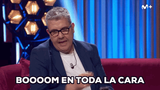 a man is sitting on a couch with the words boooom en toda la cara written below him