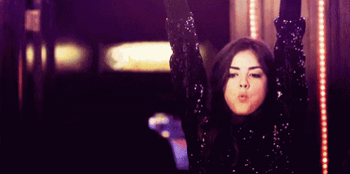a woman in a sequined dress is holding a cell phone in her hand .