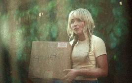 a woman is holding a cardboard box that says kitchen