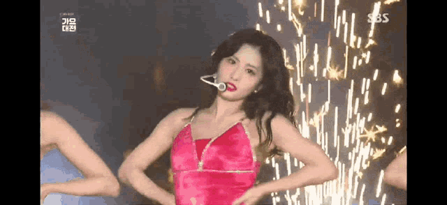 a woman in a red dress is dancing on a stage with fireworks in the background