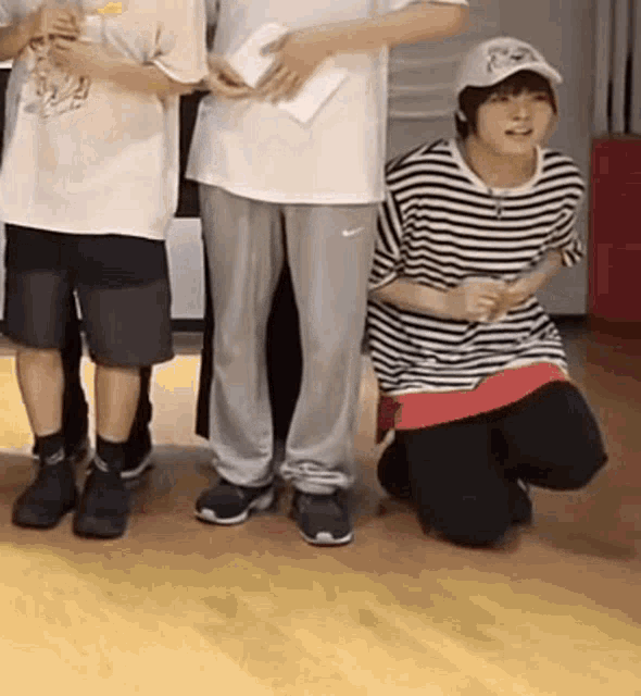 a group of young men are standing next to each other on a wooden floor in a room .