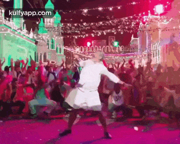 a man is dancing on a stage in front of a crowd .