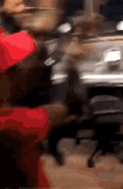 a blurry picture of a man in a red hat sitting at a desk .