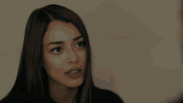 a woman with long dark hair is looking at the camera