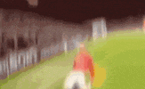 a blurry picture of a soccer player kicking a ball on a field .