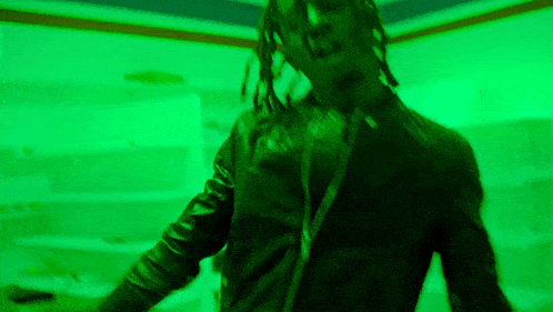 a man in a black leather jacket is standing in front of a green wall .