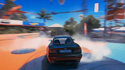 a car is driving down a road with a hot wheels sign in the background