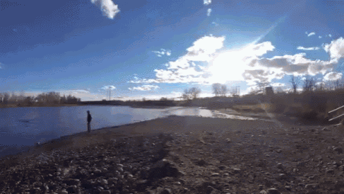 a person standing on a rocky beach near a lake