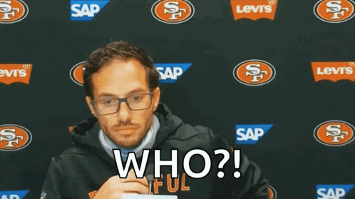 a man wearing glasses says " who " in front of a san francisco 49ers logo