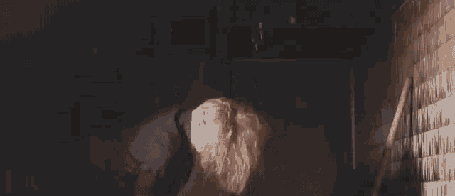 a woman is bending over in a dark room with a shovel in her hand .