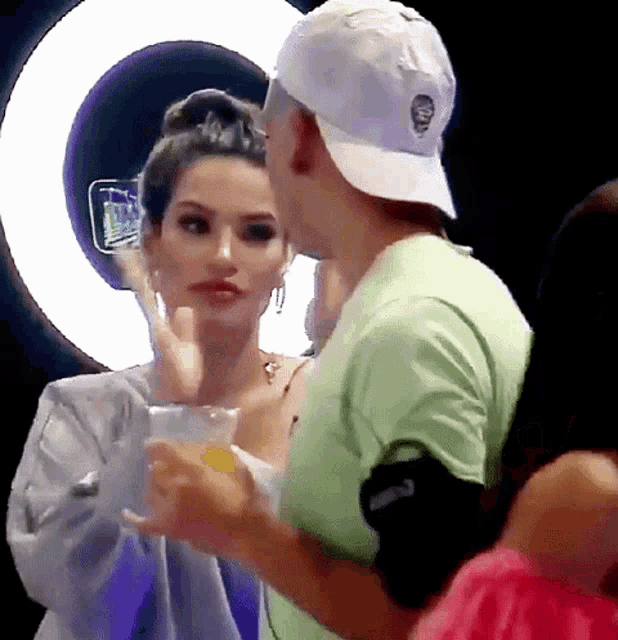 a man and a woman are standing next to each other and the man is wearing a white hat with a skull on it