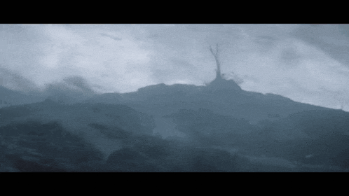 a silhouette of a tree on top of a mountain with a cloudy sky in the background