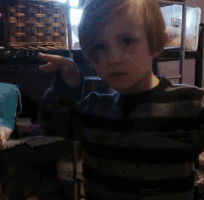 a young boy in a striped shirt is standing in front of a basket