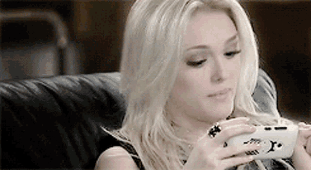 a woman is sitting on a couch holding a cell phone with the letter x on it