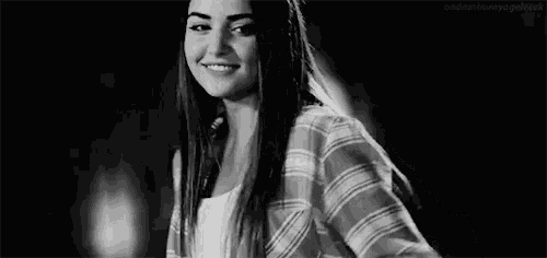 a woman in a plaid shirt is smiling and making a heart shape with her hands .
