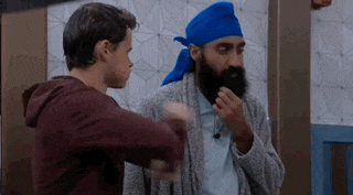 a man with a beard and a blue turban is standing next to another man in a room .