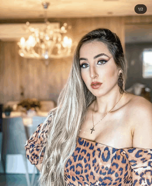 a woman wearing a leopard print top has a cross necklace on her neck