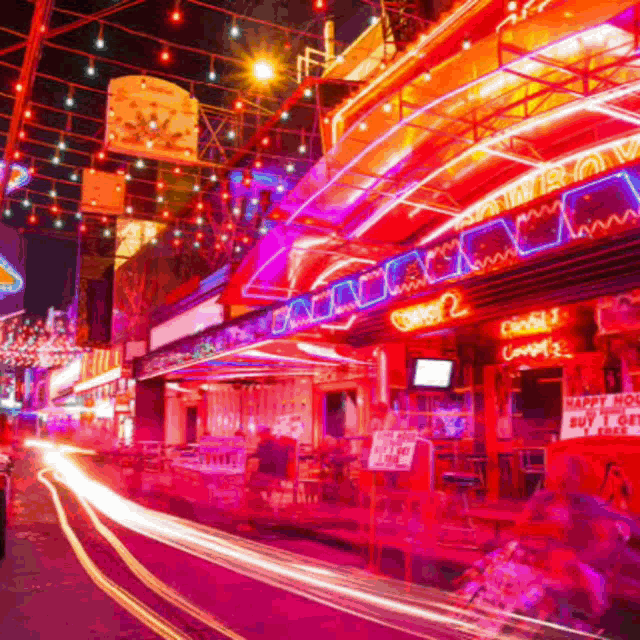 a busy street at night with a sign that says " happy hour "