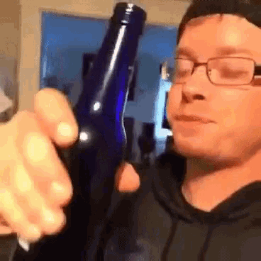 a man wearing glasses is holding a blue bottle