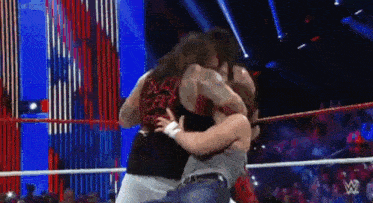 two men are wrestling in a wrestling ring .