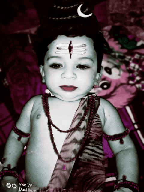 a baby is dressed up as a deity with a crescent moon on his head