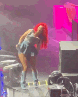 a woman with red hair is standing on a stage with a microphone in her hand