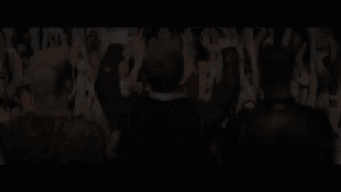 a group of people are standing in front of a crowd of people with their hands in the air .