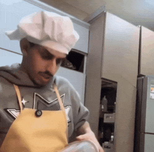 a man wearing a chef 's hat and apron is cooking in a kitchen