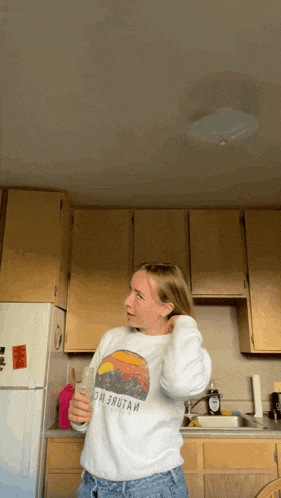 a woman in a kitchen wearing a sweatshirt that says homer stout