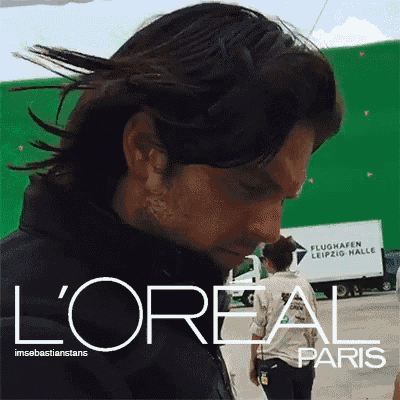 a man with long hair is standing in front of a white truck that says l'oreal paris