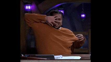 a man in a brown sweater is sitting at a table with his hands on his head and says `` it 's beautiful '' .