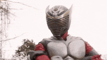 a man in a superhero costume is standing in front of trees .