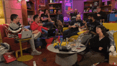 a group of people sitting around a table with a hello kitty bag in the background