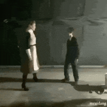 a woman and a boy are standing next to each other on a dark street .