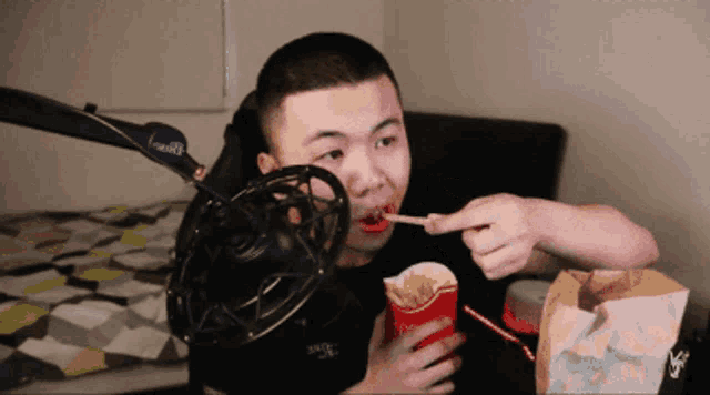 a man is eating french fries in front of a microphone that says i-wolf on it