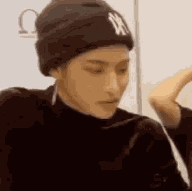 a close up of a person wearing a black beanie and earrings .