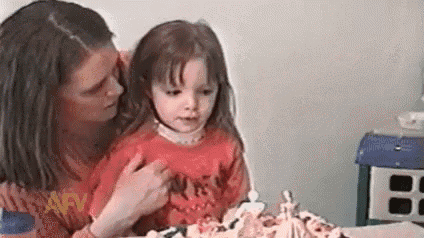 a woman is holding a little girl in front of a cake .