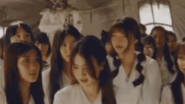 a group of young women are standing in a room and looking at something .